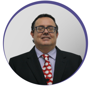 Imagem circular de um homem branco de fios pretos, óculos quadrado sorrindo para foto. Ele veste terno e gravata vermelha estampada com ovelhas brancas. É o doutor Luiz Claudio Nogueira.