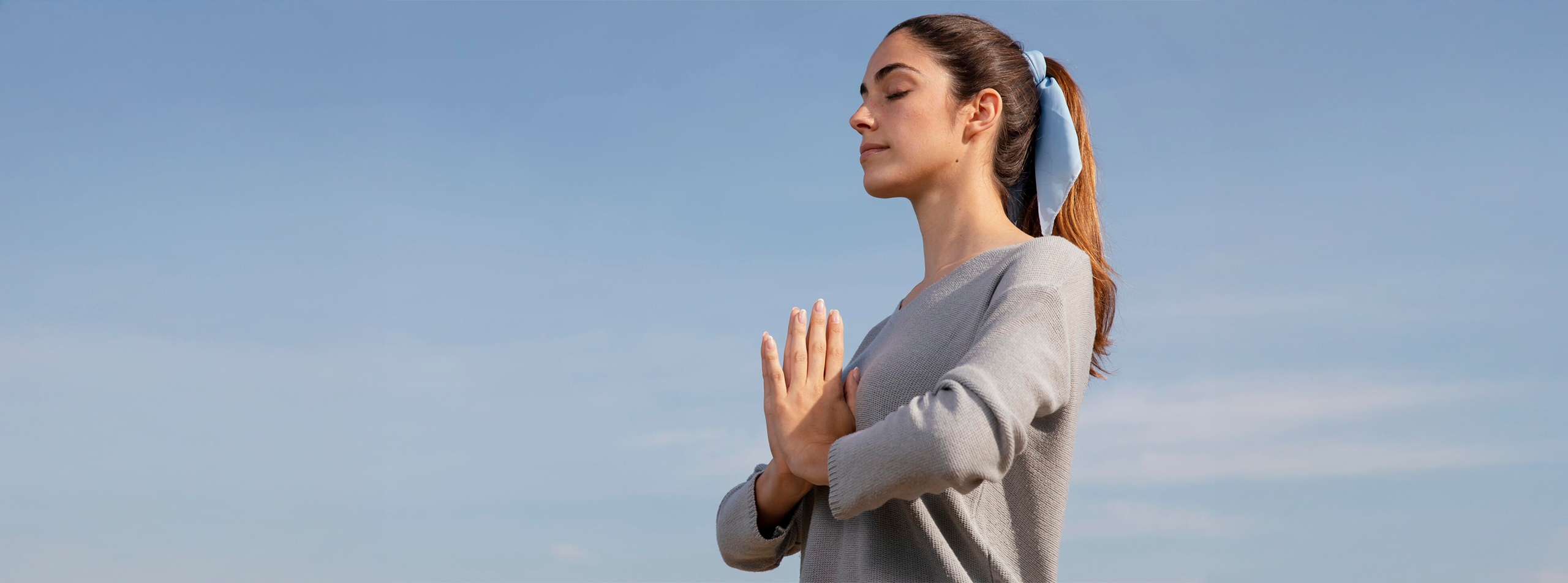 Mulher jovem em pé de mãos juntas meditando na natureza.