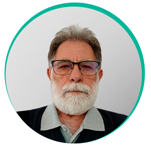 Homem branco de meia-idade, barba e bigode brancos, cabelo grisalho curto e óculos de armação cinza e quadrada. Ele veste blusa social azul e casaco preto por cima. É o dr. Ciniro Costa.